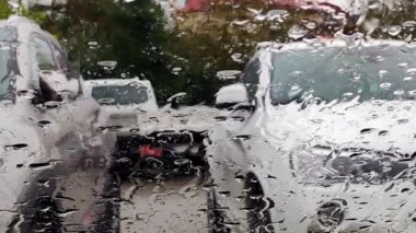 Cama yağmur yağıyor. Arka planda, arabalar otoparkta.
