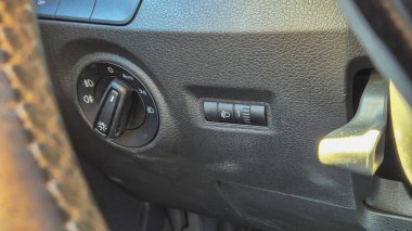 Arabanın iç kontrollerinin yakın görüntüsü, arabanın işlevselliğini ve tasarımını vurgulayan desenli gösterge panelinde bir far anahtarı ve sis ışığı kontrolü içeriyor..