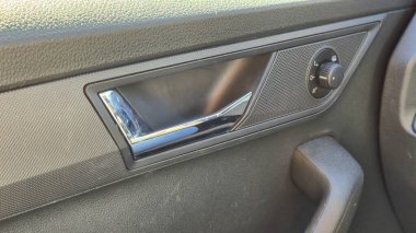 Arabanın kapısının iç tarafı, krom kapı kolu ve kontrol düğmesini gösteriyor. Bu ayrıntılı resim otomotiv detaylarının doku tasarımı ve işlevselliğini yakalar.