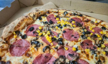 Salamlı, siyah zeytinli, mantarlı ve karton kutuda servis edilen mısırlı lezzetli pizza. Toplantılar ve partiler sırasında paylaşmak için mükemmel.
