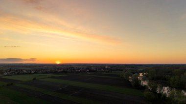 Kırsal alanlarda çarpıcı bir günbatımı. Huzurlu bir nehire yansıyan canlı renkler. Doğa severler ve sakin bir akşam atmosferi tasvir etmek için ideal..