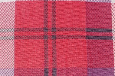 Canlı kırmızı ve siyah katran desenli kumaşın yakın plan görüntüsü karmaşık dokumasını ve dokulu yüzeyini gösteriyor. Moda tasarımı ve tekstil projeleri için ideal.