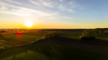 Gün batımında manzaranın havadan görünüşü gökyüzünde canlı renkler ve altın ışıkla yıkanmış sakin alanlar gösteriyor. Ufuk sakin bir ortam yaratır..