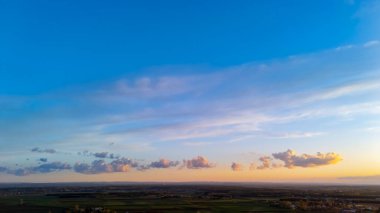Yuvarlanan tepelerin ve gün batımında yumuşak bulutlarla dolu canlı bir gökyüzünün sakin ve huzurlu bir atmosfer yarattığı engin bir manzaranın nefes kesici bir görüntüsü..