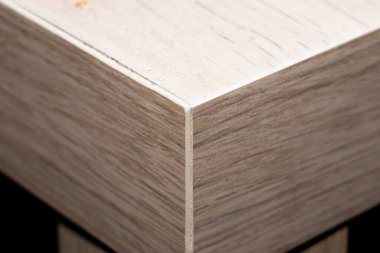 Ahşap bir yüzeyin yakın çekim görüntüsü kusursuz açılar ve dokular sergiliyor. Bu resim, iç dekorasyon ve mobilya uygulamaları için ideal işçiliği ve tasarımı vurgular.