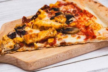 Tavuk mısır mantarı ve kırmızı sosla kaplı ahşap kesme tahtasındaki lezzetli pizza dilimi aşçılar için ideal..