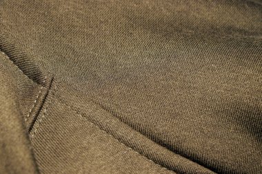 Dikiş detaylarını gösteren desenli kahverengi kumaşın yakın çekimi. Kumaş kalitesi ve tasarımı sergileyen arka plan moda tasarımları veya tekstil endüstrisi için ideal.