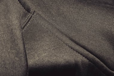 Siyah kumaş dokusunun yakın çekimi karmaşık dokuma desenleri gösterir. Genellikle giyim ve tekstil ürünlerinde kullanılır. Moda tasarımı ve malzeme analizi için ideal..