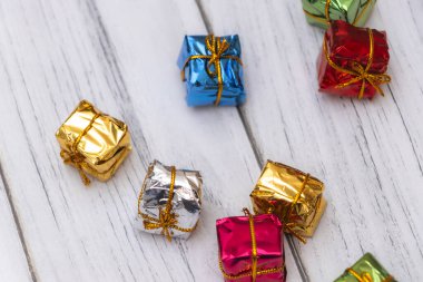 Hafif ahşap bir yüzeye saçılmış renkli hediye kutuları. Bayram kutlamaları için mükemmel. Dekorasyonlara büyüleyici bir dokunuş..