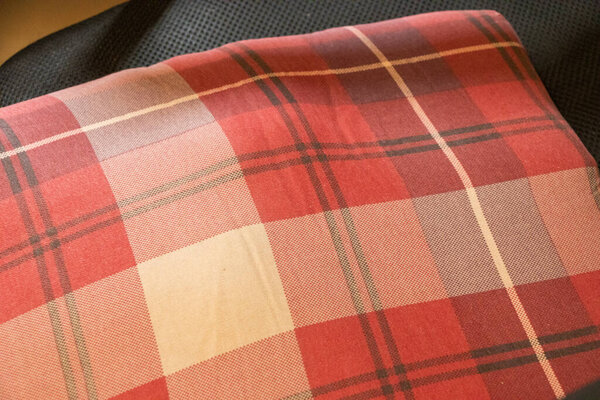 Textile fabric in a stylish plaid pattern featuring shades of red cream and grey ideal for home decor projects fashion design and upholstery applications.