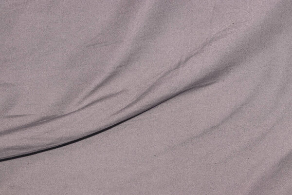 Крупный план мягко задрапированной ткани в приглушенном розовом тоне, демонстрирующий тонкие текстуры и изгибы. Идеально подходит для фонов текстильный дизайн или цвет вдохновения.