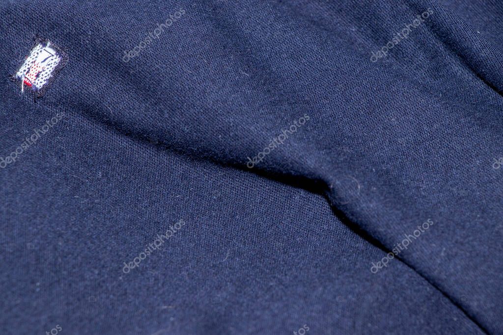 Close-up image of a navy blue fabric featuring a small logo. The texture showcases the softness and quality ideal for fashion and textile applications.