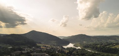 Dağların, huzurlu bir nehrin ve bulutlarla dolu dramatik bir gökyüzünün altında küçük bir kasabanın bulunduğu çarpıcı bir hava manzarası..