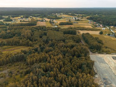 Berrak bir gökyüzü altında bereketli ormanların ve yamalı tarlaların sergilendiği sakin bir kırsal manzaranın havadan görünüşü. Güzellik ve tarım yaşam tarzlarını sergilemek için ideal..