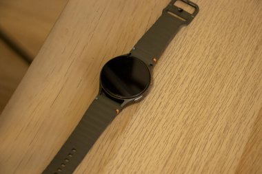 Modern bir ukala ahşap bir yüzeye dayanır. Parlak tasarımını ve lastik kayışını sergiler. Spor meraklıları ve teknoloji aletleri meraklıları için ideal..