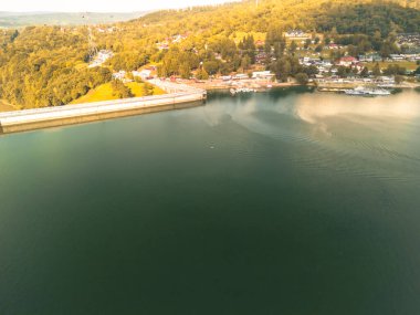 Polonya 'daki Solina Barajı' nın hava manzarası yemyeşil ve yerleşim alanlarıyla çevrili sakin suları sergiliyor. Açık hava aktiviteleri ve doğa turizmi için mükemmel..