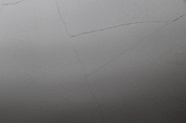 Çatlak bir gri duvar yüzeyinin yakın plan çekimleri, eskiyen eskiyme ve yaşın nüanslarını özgeçmiş ve soyut kavramlar için ideal bir şekilde yakalıyor..