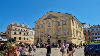 Lublin Polonya - 15 Ağustos 2025: Crown Tribunal 'da, tarihi mimari yakınlarındaki açık mavi gökyüzünün altında yürüyen insanları gösteren hareketli bir sahne.
