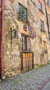 Lublin Polonya - 15 Ağustos 2025: Tarihi şehirde, yıpranmış duvarında sanatsal bir kelebek tesisi bulunan eski bir apartman dairesi.