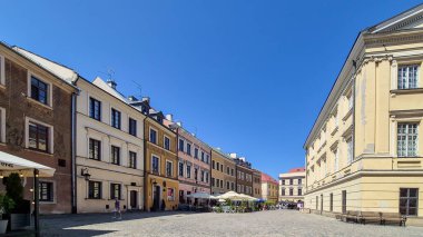 Lublin Polonya - 15 Ağustos 2025: Güneşli bir günde Eski Kent Pazar Meydanı 'nın canlı bir görüntüsü, tarihi binaları ve açık hava kafeleri ve dükkanları gezen insanları gözler önüne seriyor.