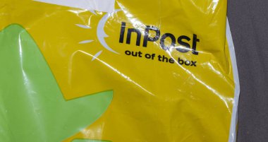 Varşova Polonya - 8 Ekim 2025: InPost teslimat çantasının yakın çekimi, nakliyede çevre dostu ve kolaylığı simgeleyen parlak sarı bir renk ve yeşil yaprak motifleri sergiliyor.