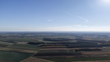 Açık mavi gökyüzünün altındaki geniş tarım alanlarının havadan görünüşü yeşil kahverengi ve sarı bir parçayı gösteriyor. Kırsal bölgeleri ve tarımı temsil etmek için mükemmel..