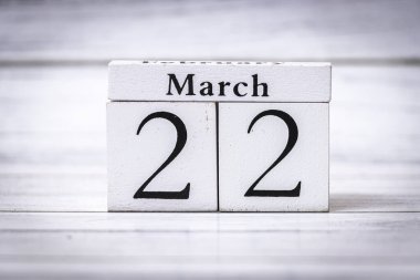 22 ve Mart tarihlerini gösteren ahşap bir takvimin yakın plan görüntüsü. Mevsimsel dekorasyon ve planlama için mükemmel bir ahşap arka planda yerleştirilmiş..