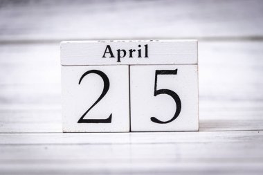 25 Nisan, eski tarz bir takvim bloğunda, bahar aylarındaki etkinlik ve kutlamaların tarihini temsil eden hafif ahşap bir arkaplan karşısında sergilendi.