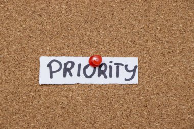 İş yönetimi ve organizasyonun önemini sembolize eden mantar panoya yapıştırılmış el yazısı sözcük özellikleri günlük hayatta etkili önceliklerin hatırlatıcısı.