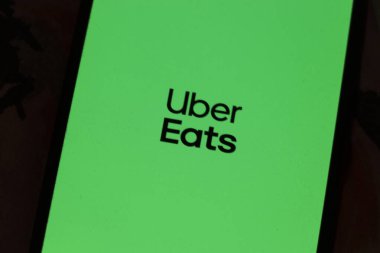 Varşova Polonya - 6 Kasım 2025: Uber Eats logosunu canlı yeşil arkaplanda gösteren akıllı telefon ekranının yakın çekimi gıda dağıtım hizmetlerini gösteriyor.