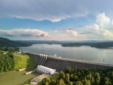 Solina Poland - 29 Haziran 2024: Solina Barajı 'nın yemyeşil ve gökyüzünü yansıtan sakin bir göl ile çevrili geniş yapısını gösteren hava manzarası.