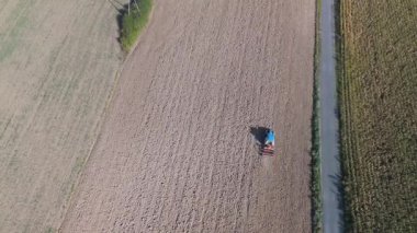 Uçsuz bucaksız tarla süren bir traktörün hava görüntüsü, tanımlanmış toprak kalıpları bırakıyor..