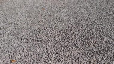 Küçük taşlar ve gölgelerle açık bir alana açılan çakıl yolunun havadan çekilmiş görüntüsü..