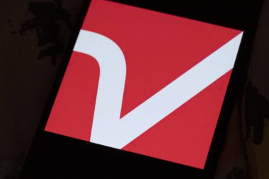 Varşova Polonya - 6 Kasım 2025: Modern markalaşma ve tasarımı temsil eden bir telefon ekranında V harfini gösteren canlı kırmızı bir logonun yakın çekimi.