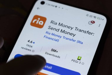 Varşova Polonya - 6 Kasım 2025: Ria Money Transfer uygulamasını gösteren ve finansal hizmetler için istatistikleri indiren akıllı telefon ekranının yakın çekimi.