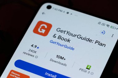 Varşova Polonya - 6 Kasım 2025: GetYourGuide uygulamasının 4.9 yıldızlık derecesini gösteren ve istatistik indiren akıllı telefon ekranının yakın çekimi.