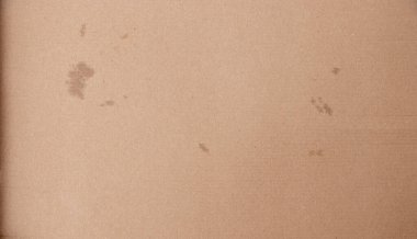 Çeşitli leke ve işaretleri gösteren desenli kahverengi bir kağıdın yakından görüntüsü. Bu yüzey el sanatları veya yaratıcı projeler için kullanılabilir.