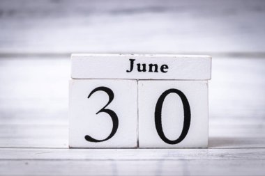 Tahta takvim blokları, ayın sonunu ve Temmuz ayına geçişi sembolize eden 30 Haziran 'ı gösteriyor. Zaman yönetimi ve aylık planlama kavramları için ideal.