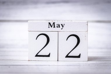 22 Mayıs tarihini minimalist bir dekorda gösteren ahşap bir takvim bloğu. Bu eşyalar ev dekorasyonu ve mevsimlik dekorasyon için mükemmel..