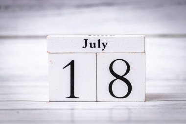 18 Temmuz tarihini gösteren tahta bir takvim bloğu. Beyaz arkaplan, çeşitli durumlar ve hatırlatıcılar için uygun basit ama zarif tasarımı vurgular.