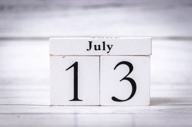 Tahta takvim blokları 13 Temmuz tarihini gösteriyor. Bu basit ama zarif dekorasyon, ev ofisi veya etkinlik ayarlarındaki kutlamaları veya hatırlatıcıları sembolize edebilir.