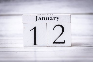 12 Ocak 'ta gösterilen beyaz ahşap takvim. Belirli bir tarihin bu görsel temsili günlük hayatta organizasyon ve zaman yönetimini simgeler..