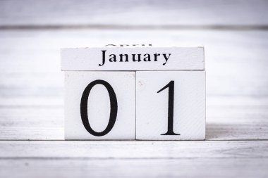 El yapımı blok takvimi 01 Ocak 'ta ahşap bir arka planda gösteriliyor. Yeni başlangıçları ve yıllık etkinlikleri temsil etmek için ideal.