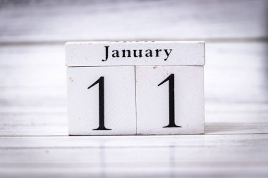 11 Ocak tarihini gösteren tahta bir takvim beyaz ahşap bir yüzeyde dinleniyor. Organizasyon veya zaman yönetimi temaları için ideal.