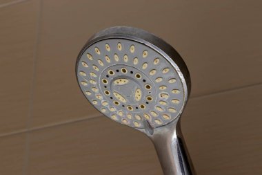 Yuvarlak şeklini ve banyo estetiğini ve işlevselliğini geliştirmek için ideal çoklu su çıkış deliklerini gösteren ev kullanımı için tasarlanmış modern bir duş başlığının yakın çekimi.