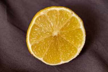 Koyu bir yüzeyde yarım bir limon sulu dokusunu ve canlı sarı rengini vurguluyor. Gıda ile ilgili projeler ve mutfak sunumları için ideal.