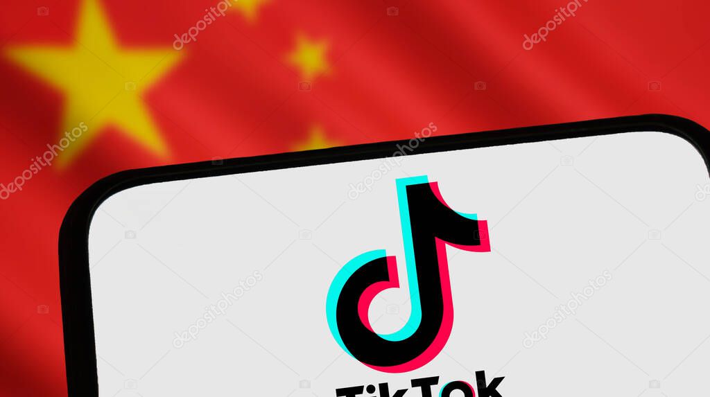 Warsaw Poland - November 8 2025: TikTok logo displayed on smartphone screen symbolizing social media influence. Background features blurred Chinese flag colors.