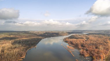 Sükunet içindeki Vistula Nehri 'nin hava manzarası Kazimierz yakınlarındaki renkli sonbahar manzarasında canlı ağaçlar ve mavi gökyüzünün altında dingin bir su sergiliyor..