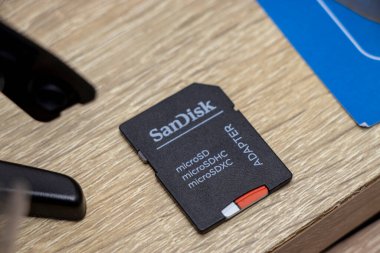 Varşova Polonya - 13 Kasım 2025: SanDisk mikro hafıza kartı adaptörünün ahşap bir yüzeye yerleştirilmiş yakın çekim görüntüsü.