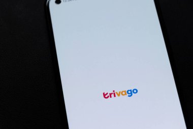 Varşova Polonya - 13 Kasım 2025: Trivago logosunu otel ve seyahat hizmetlerini sembolize eden beyaz bir arka planda gösteren akıllı telefonun yakın görüntüsü.